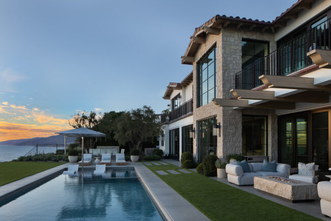 A large pool and patio area with a house in the background.