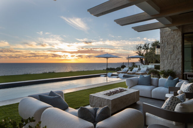 A patio with couches and fire pit overlooking the ocean.