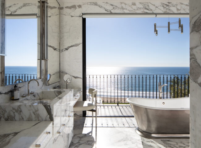 A bathroom with a large window and a view of the ocean.