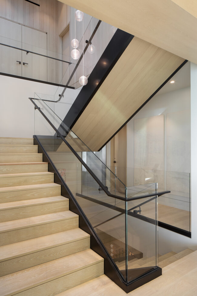 A staircase with glass railing and wood steps.