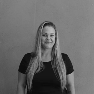 A black and white photo of a woman standing in front of a wall.