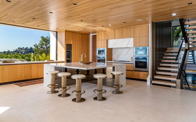 A kitchen with a large island and stools in it