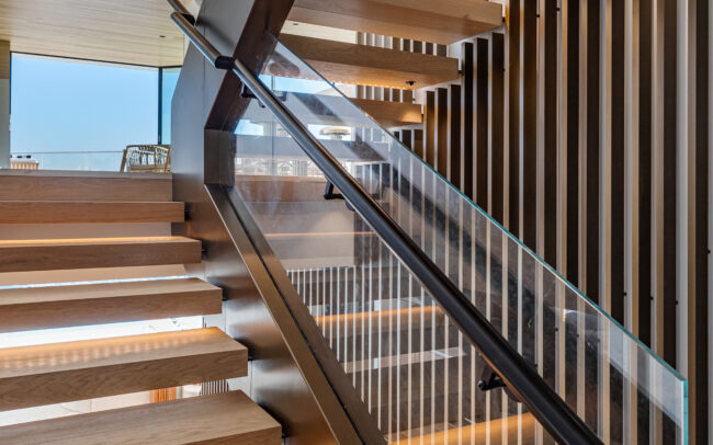 A wooden staircase with glass railing and wood steps.