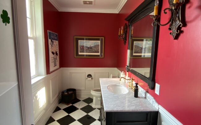 A bathroom with red walls and black and white checkered floor.
