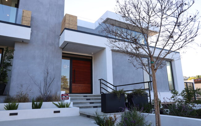 A modern house with a black railing and white door.