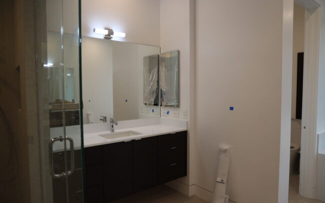 A bathroom with a large mirror and a glass shower door.