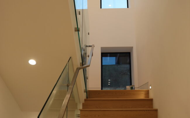 A staircase with wooden steps and glass railing.