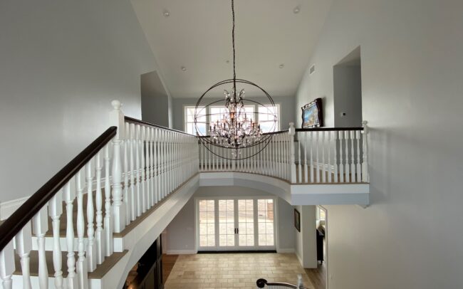 A large white staircase with a chandelier hanging from the ceiling.