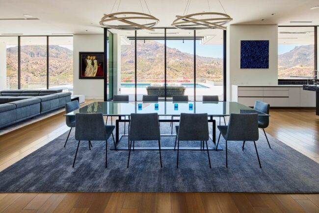 A large dining room table with chairs and a view of mountains.