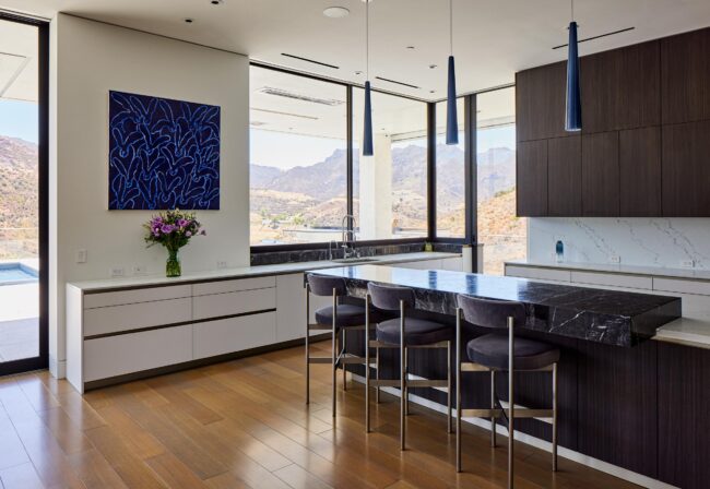 A kitchen with a large window and a view of the mountains.