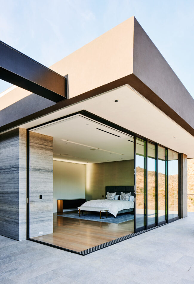 A bedroom with sliding glass doors open to the outside.