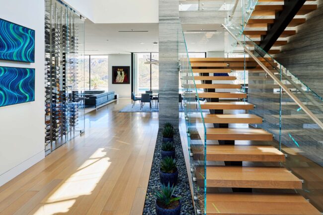 A large open floor plan with glass walls and wooden stairs.