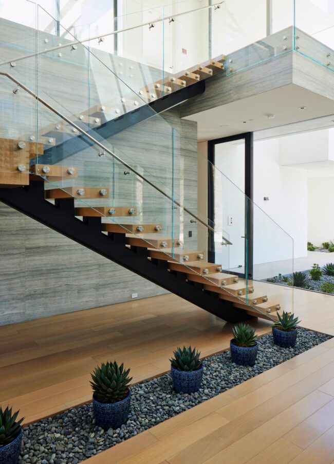 A staircase with plants and glass railing.