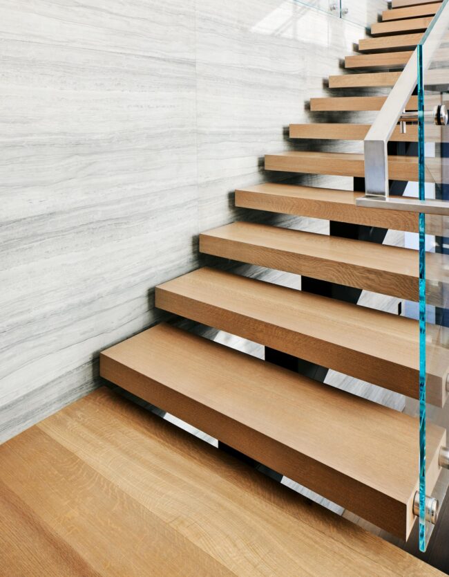 A wooden staircase with glass railing and wood steps.