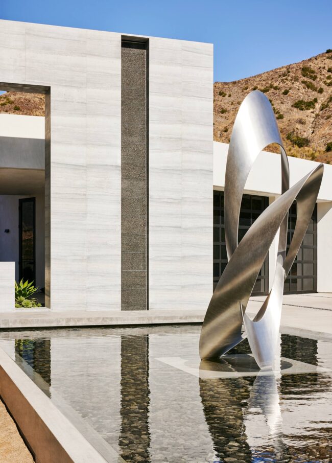 A sculpture of two intersecting blades in front of a building.