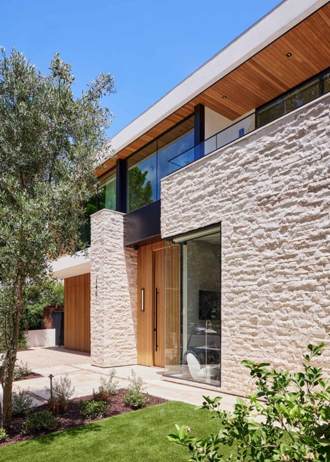 A modern house with stone walls and windows.