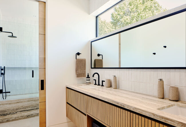 A bathroom with a large mirror and wooden vanity.