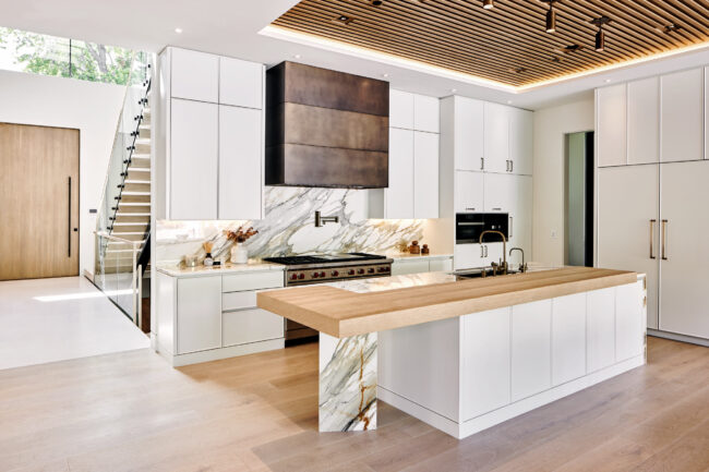 A kitchen with white cabinets and wood island.