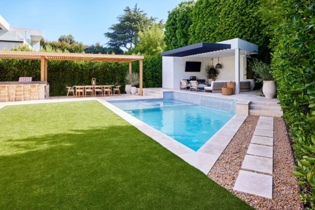 A pool with an outdoor cabana and grass.