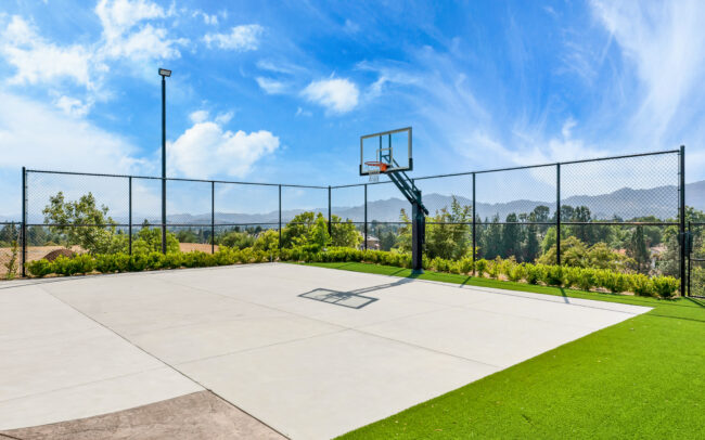 A basketball court with a net and grass.