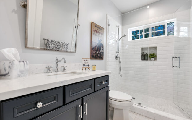 A bathroom with white tile and black cabinets.
