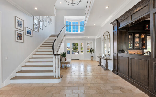 A large foyer with a staircase and tiled floors.