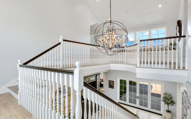 A large white staircase with a chandelier in the middle of it.