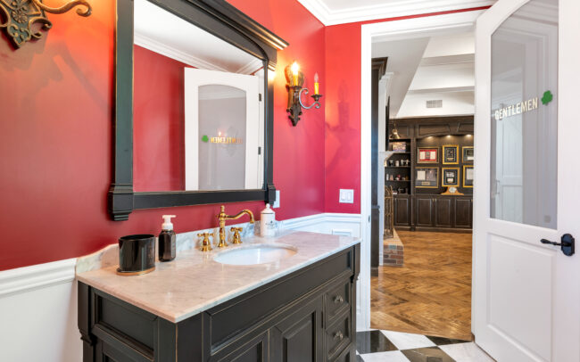 A bathroom with red walls and black cabinets.